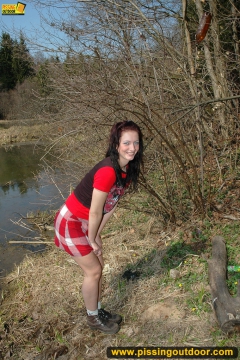 Outdoor pissing on the dry grass on a pond shore - N